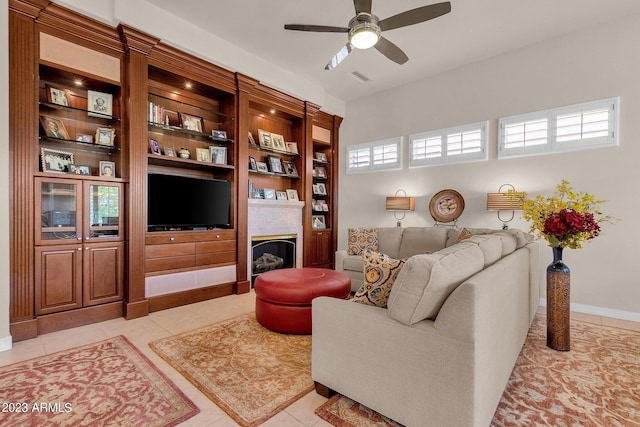 living room featuring light tile patterned floors, baseboards, visible vents, a ceiling fan, and a fireplace