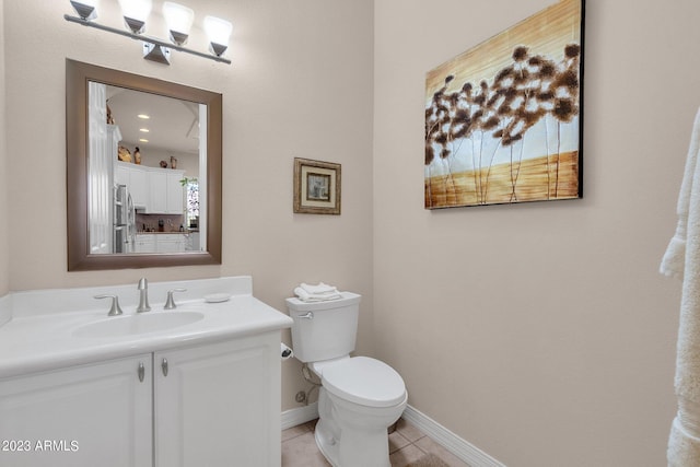 bathroom with toilet, tile patterned flooring, vanity, and baseboards