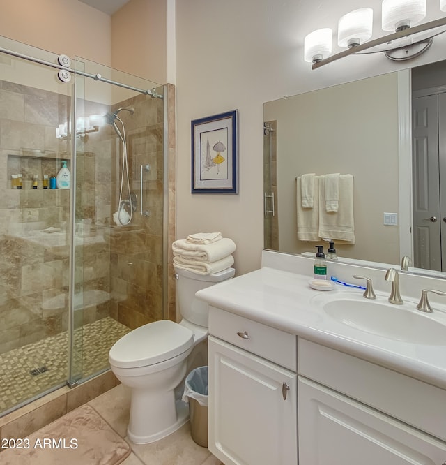 bathroom with a shower with door, vanity, tile patterned floors, and toilet