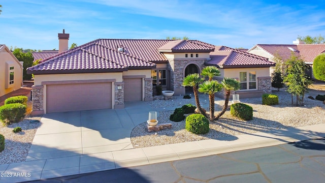 mediterranean / spanish-style house featuring a garage, concrete driveway, stone siding, a tiled roof, and stucco siding