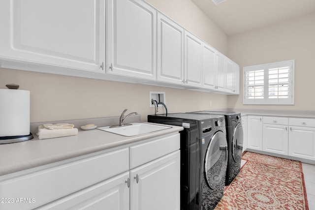 laundry area featuring washing machine and dryer, cabinet space, a sink, and light tile patterned floors