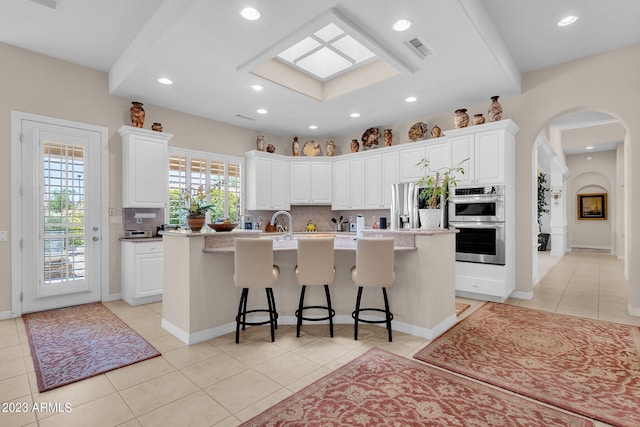 kitchen with appliances with stainless steel finishes, tasteful backsplash, and an island with sink