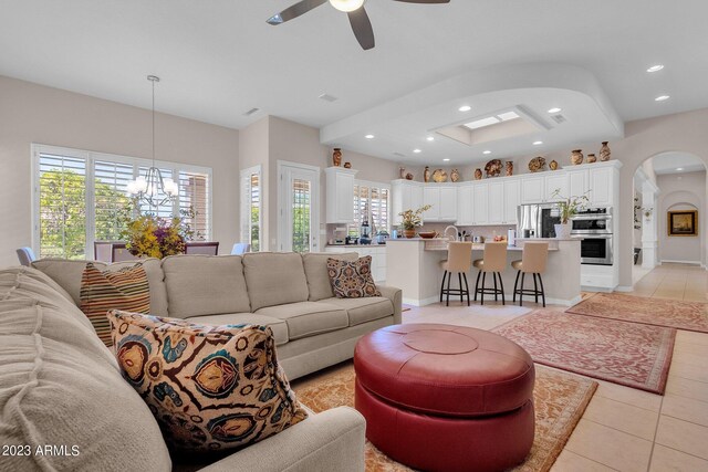 living room with light tile patterned floors, a wealth of natural light, and ceiling fan