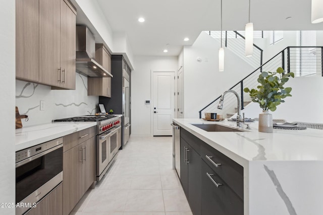 kitchen featuring appliances with stainless steel finishes, a sink, wall chimney exhaust hood, and modern cabinets