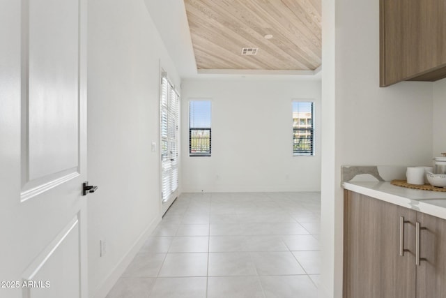 hall featuring plenty of natural light, wood ceiling, light tile patterned flooring, and visible vents