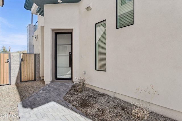 entrance to property featuring a gate and stucco siding