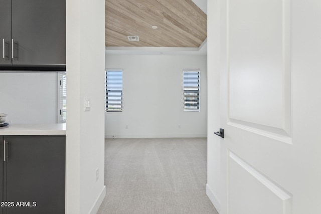 hall featuring baseboards, carpet, and wooden ceiling
