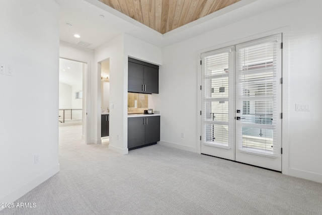doorway with wooden ceiling, baseboards, and light carpet
