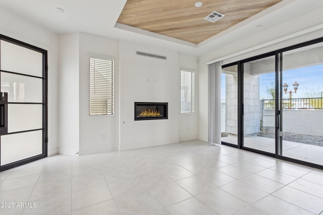 unfurnished living room featuring visible vents, a glass covered fireplace, light tile patterned flooring, and wooden ceiling