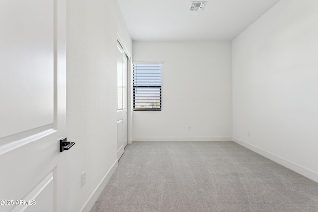 spare room featuring baseboards, light colored carpet, and visible vents