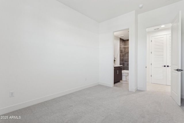 unfurnished bedroom featuring baseboards, light carpet, and connected bathroom
