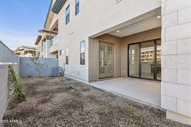 rear view of house with stucco siding, a patio, fence, and cooling unit