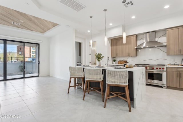 kitchen featuring light countertops, visible vents, premium range, and wall chimney exhaust hood