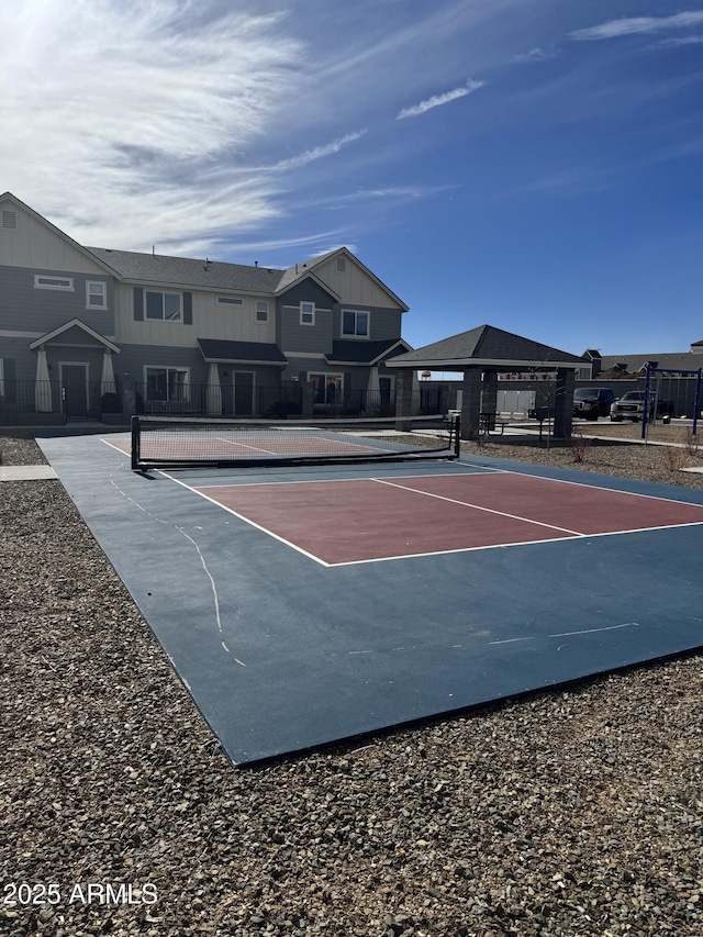 view of sport court featuring a tennis court, a residential view, and fence