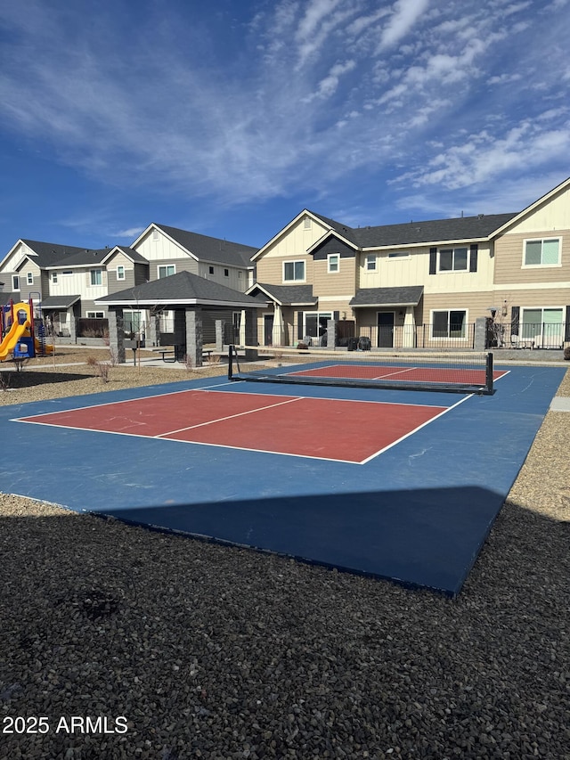 view of basketball court featuring a tennis court, a residential view, and fence