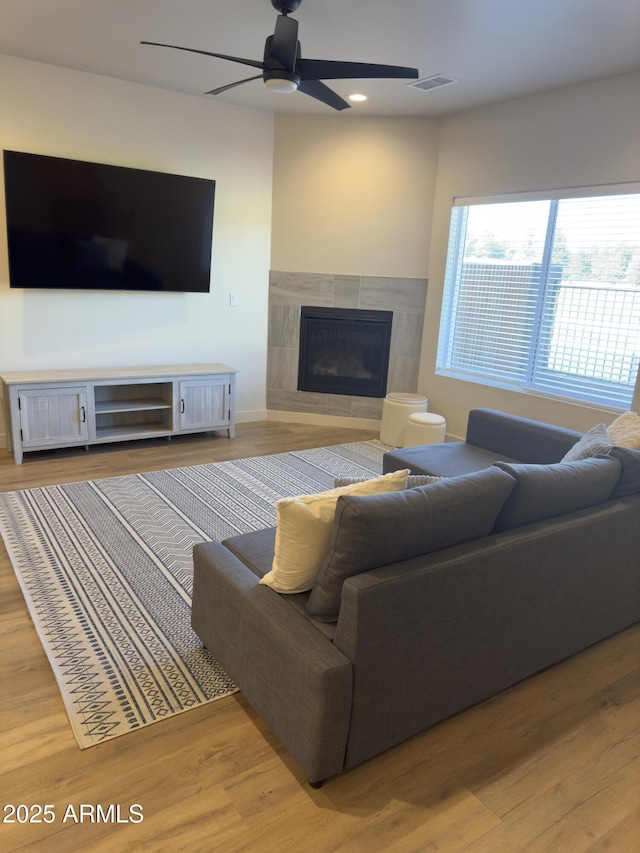 living room with recessed lighting, wood finished floors, visible vents, a ceiling fan, and a tiled fireplace