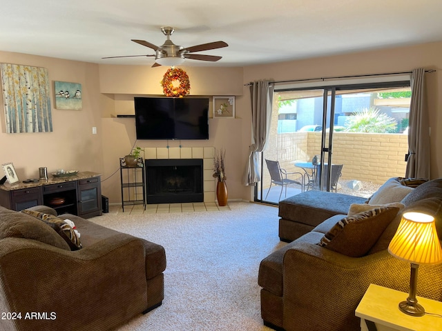 carpeted living room featuring ceiling fan and a tiled fireplace