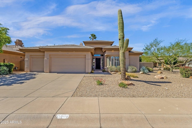 prairie-style house with an attached garage, stucco siding, a tile roof, and concrete driveway