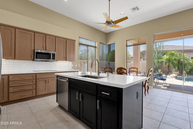 kitchen featuring a sink, stainless steel appliances, a ceiling fan, tasteful backsplash, and visible vents