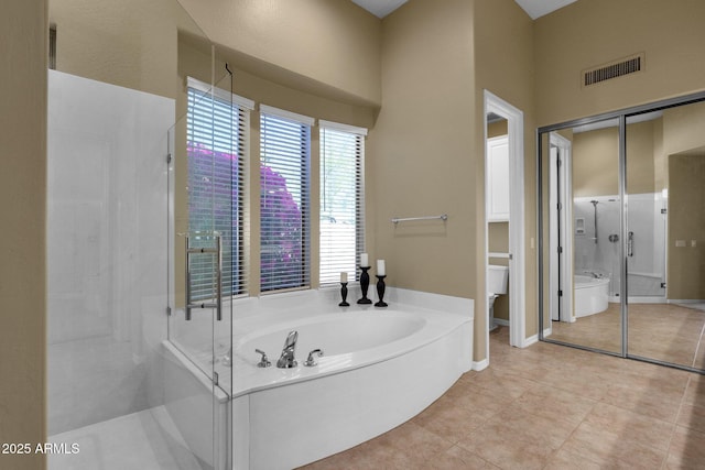 full bathroom featuring tile patterned flooring, toilet, baseboards, visible vents, and a bath