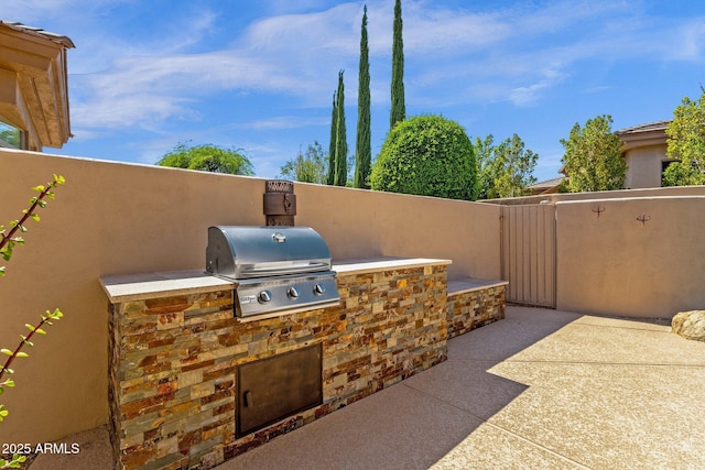 view of patio featuring exterior kitchen, fence, and a grill