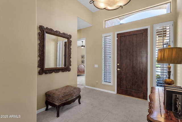 foyer entrance with light tile patterned floors, baseboards, and a towering ceiling
