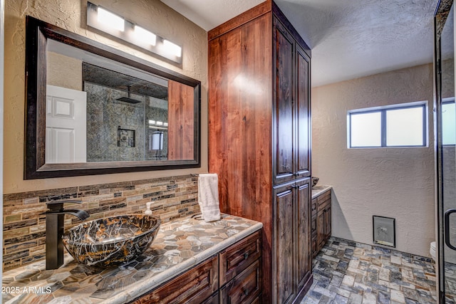 6520 E Peak View Rd, Cave Creek, AZ 85331 - bathroom featuring a textured wall, vanity, a shower stall, brick patterned flooring, and backsplash