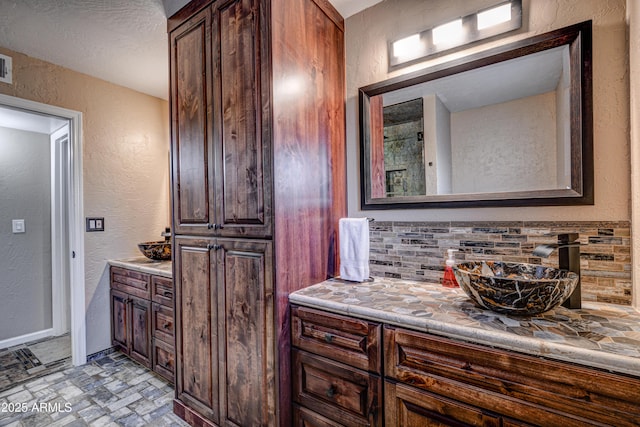 6520 E Peak View Rd, Cave Creek, AZ 85331 - full bathroom with a textured wall, vanity, and decorative backsplash