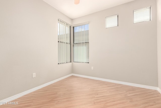 empty room with ceiling fan, light wood-style floors, and baseboards