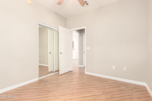 unfurnished bedroom with a closet, baseboards, and light wood-style flooring