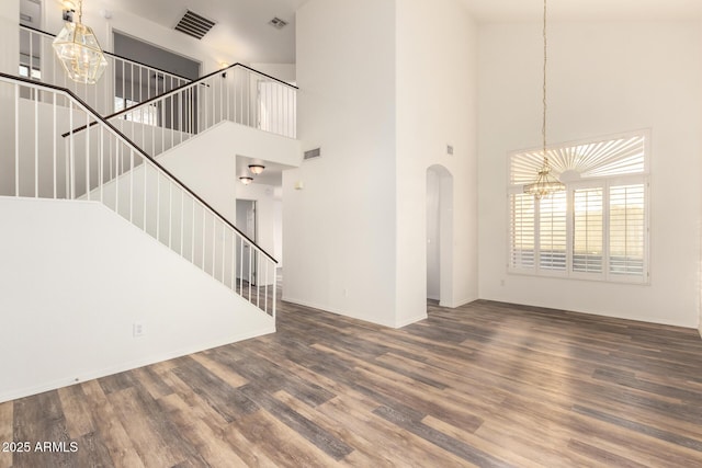 8450 S Stephanie Ln, Tempe, AZ 85284 - unfurnished living room with a chandelier, a towering ceiling, arched walkways, wood finished floors, and stairs