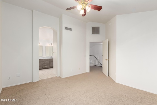 8450 S Stephanie Ln, Tempe, AZ 85284 - empty room featuring light carpet, ceiling fan, baseboards, lofted ceiling, and arched walkways