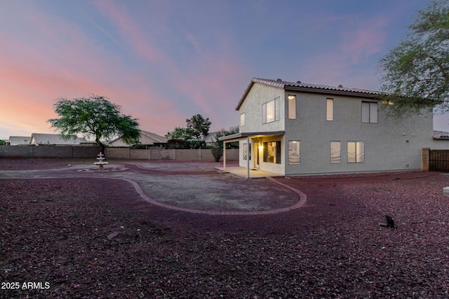 8450 S Stephanie Ln, Tempe, AZ 85284 - back of house at dusk featuring a patio area, a fenced backyard, a tile roof, and stucco siding
