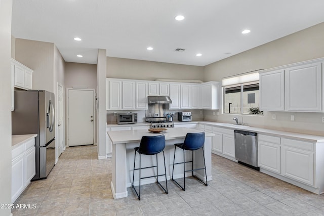 kitchen featuring sink, a breakfast bar area, stainless steel appliances, white cabinets, and a kitchen island