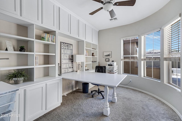 office space with built in features, ceiling fan, and carpet