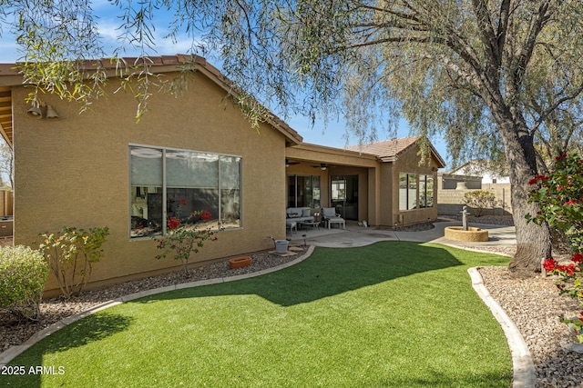 rear view of property with ceiling fan, a patio area, and a lawn