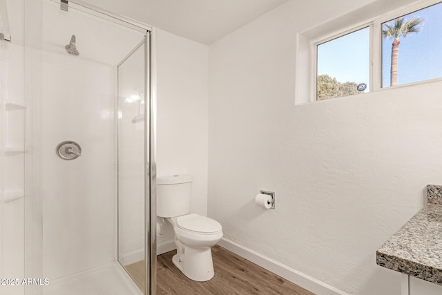 bathroom featuring wood-type flooring, walk in shower, vanity, and toilet