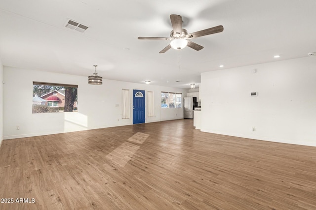 unfurnished living room with hardwood / wood-style flooring, ceiling fan, and a healthy amount of sunlight