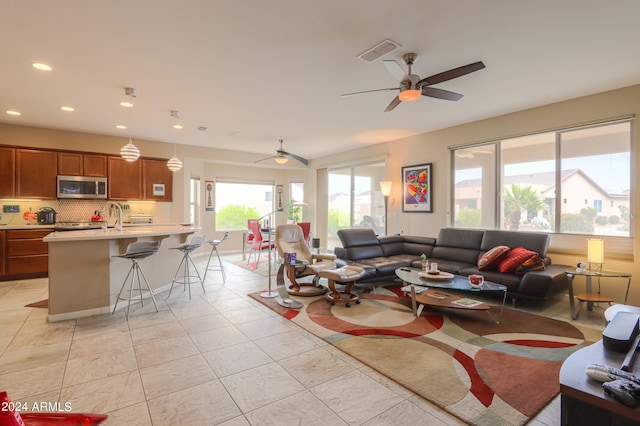 tiled living room featuring ceiling fan and sink