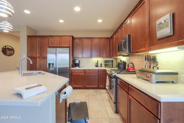 kitchen with sink, light tile floors, hanging light fixtures, appliances with stainless steel finishes, and backsplash