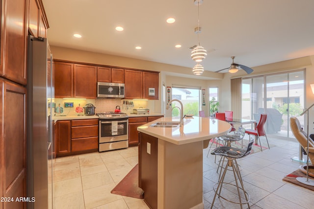 kitchen with stainless steel appliances, ceiling fan with notable chandelier, tasteful backsplash, hanging light fixtures, and sink