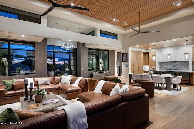 8328 E Whisper Rock Trl, Scottsdale, AZ 85266 - living room with recessed lighting, visible vents, light wood-style flooring, a towering ceiling, and ceiling fan with notable chandelier