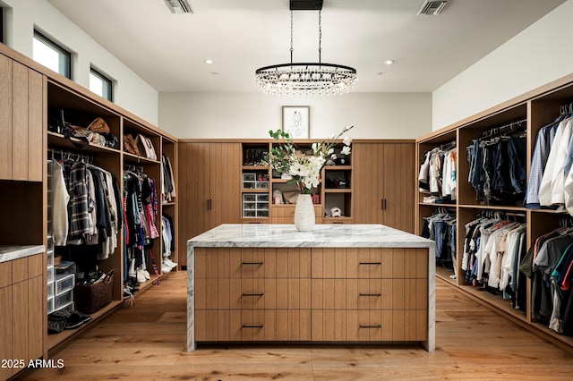 8328 E Whisper Rock Trl, Scottsdale, AZ 85266 - walk in closet featuring light wood finished floors, visible vents, and a notable chandelier