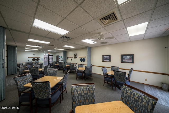 carpeted dining area with ceiling fan and a drop ceiling