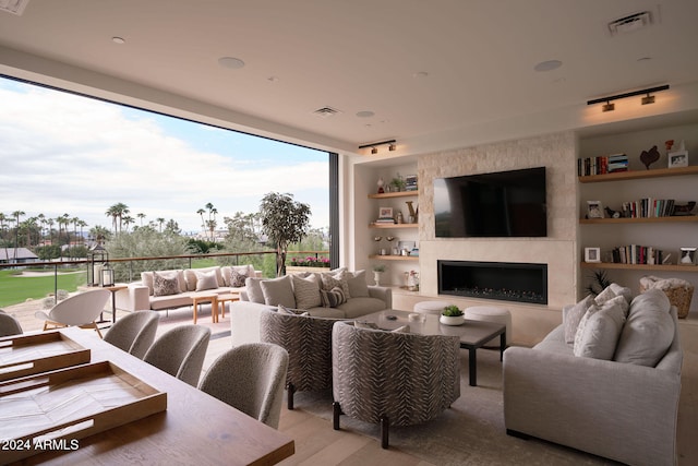 living room featuring light hardwood / wood-style floors, a large fireplace, and track lighting