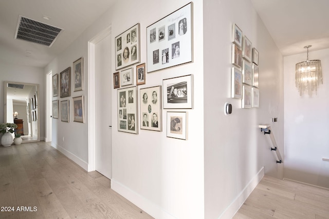 hall with a chandelier and light hardwood / wood-style floors