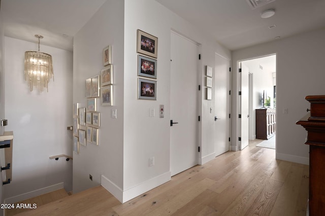 hallway featuring a notable chandelier and light hardwood / wood-style floors