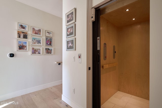 corridor featuring elevator and light hardwood / wood-style flooring