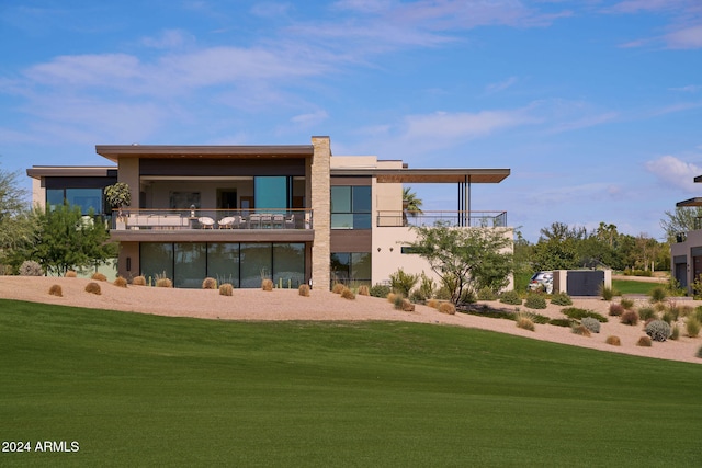 back of house featuring a balcony and a yard