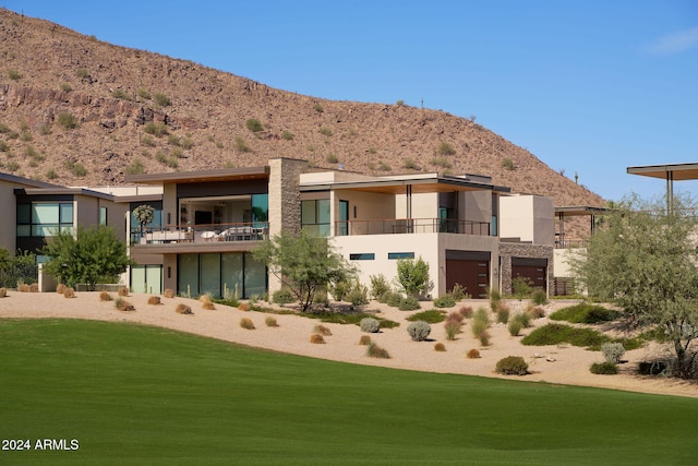 rear view of house with a mountain view and a yard